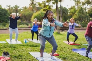 Fit multiracial senior people doing yoga exercise at city park - Mental health concept